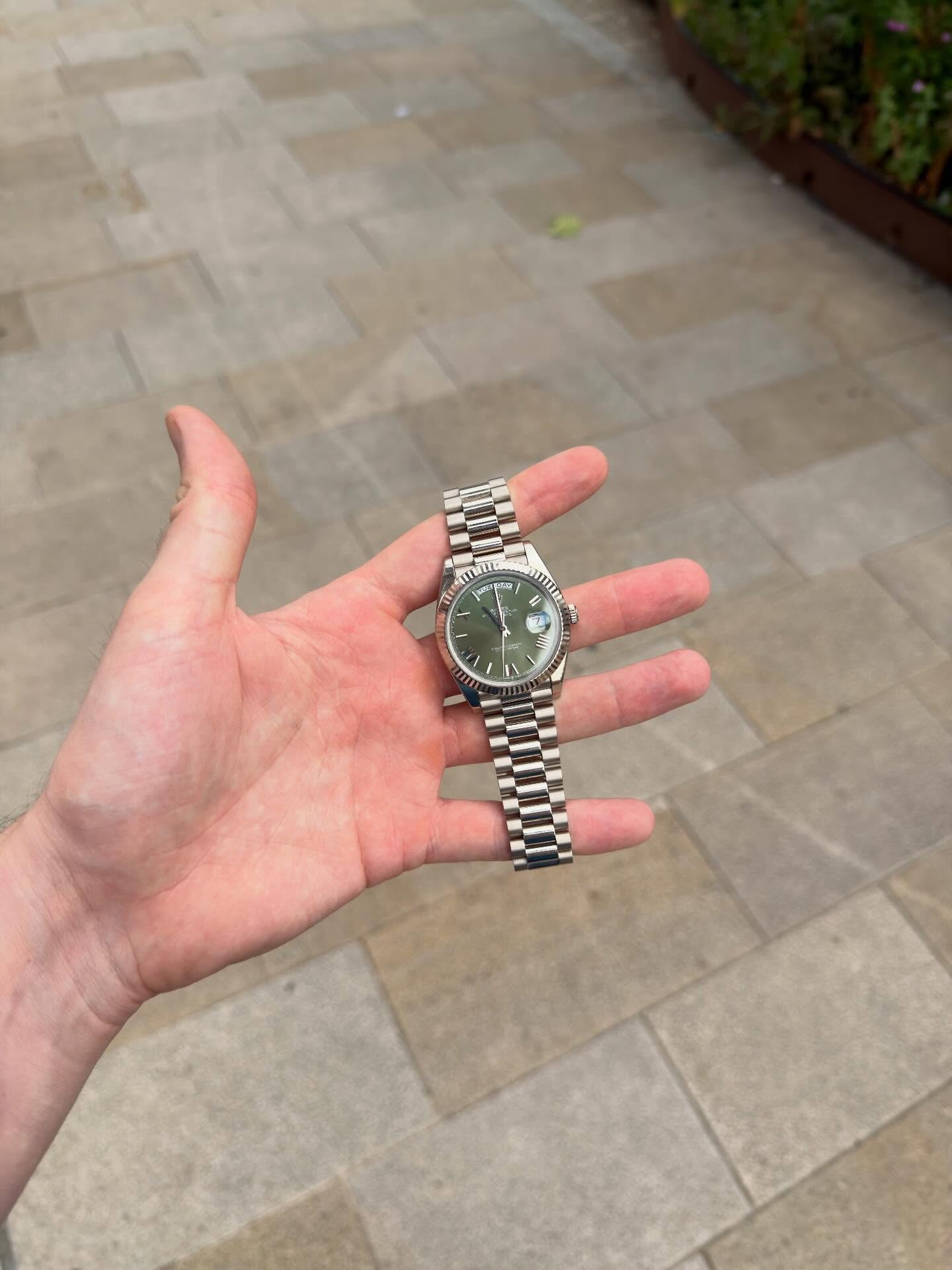 A Rolex Day-Date with a green dial, held in hand